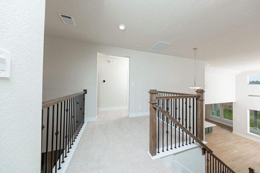 Second floor hallway showcasing the gorgeous stair railing and views of the 1st floor living space.