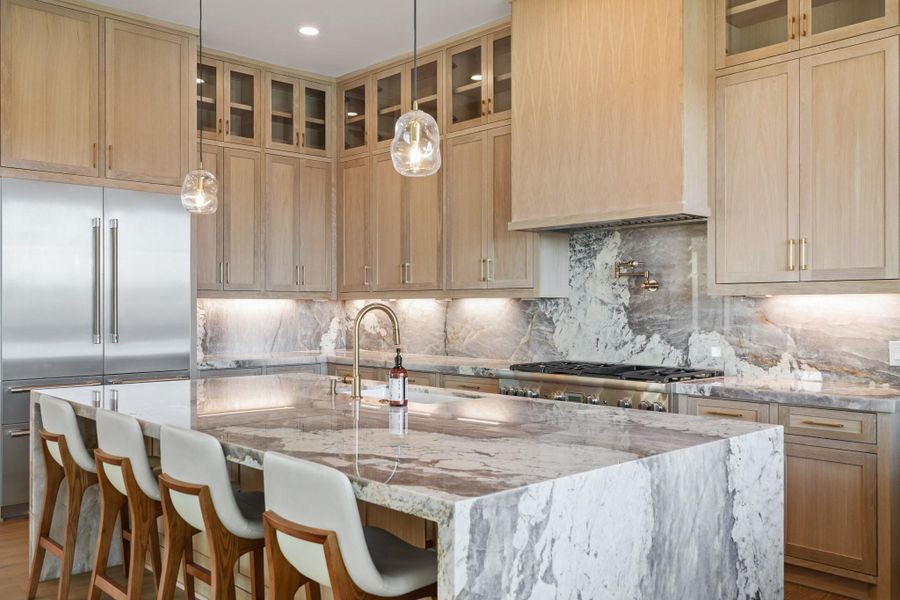 Another view of the beautiful kitchen with quartzite waterfall countertops and a matching backsplash.
