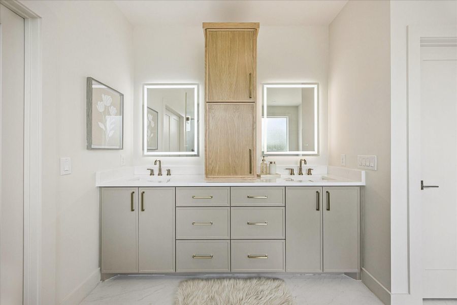 The custom vanity is as beautiful as it is practical, with oversized drawers, a center storage tower and backlit mirrors that keep everyday routines organized while adding a polished, spa-like feel.