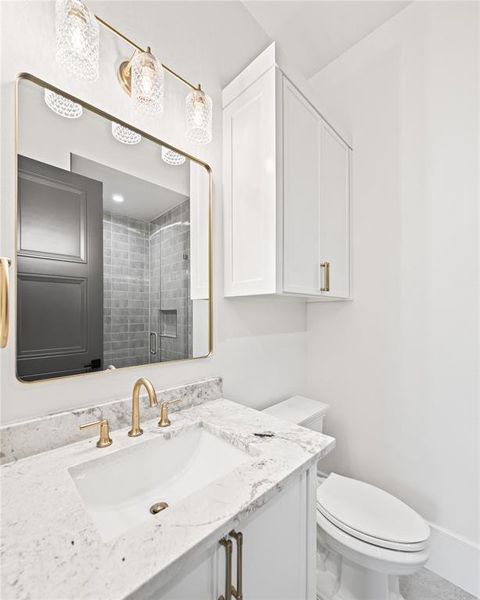 Bathroom featuring a white vanity with an integrated sink, a speckled countertop, and gold-toned fixtures