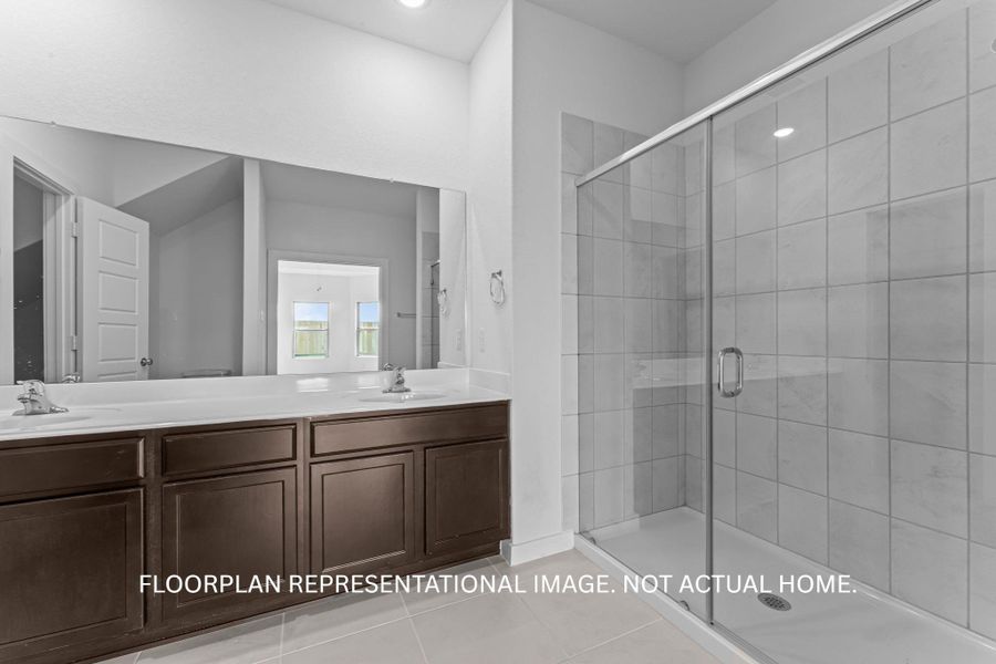 Double vanities and a spacious glass-enclosed shower create a practical and well-appointed bathroom.