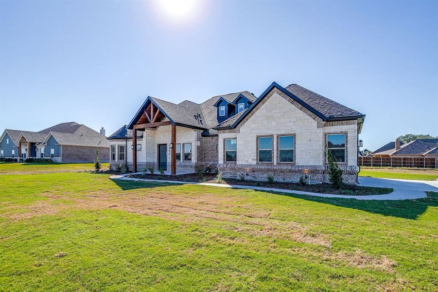 French provincial home featuring a front yard, stone siding, and brick siding