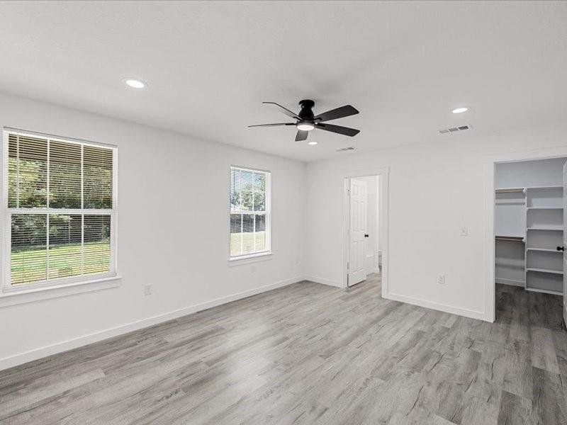 Unfurnished bedroom with a spacious closet, light wood finished floors, recessed lighting, and ceiling fan
