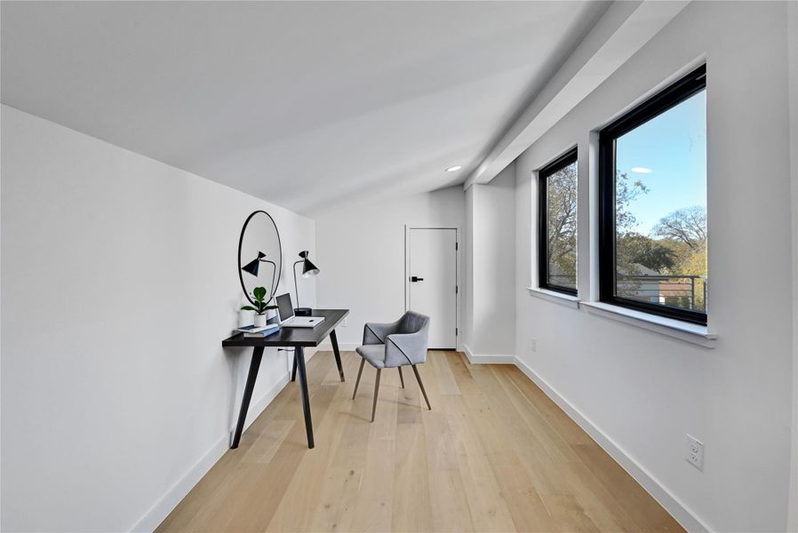 Hallway featuring light hardwood / wood-style floors and vaulted ceiling