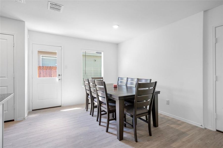 Dining area featuring wood-finish flooring, white walls, and a door with a clear glass insert Dining area featuring wood-finish flooring, white walls, and a door with a clear glass insert