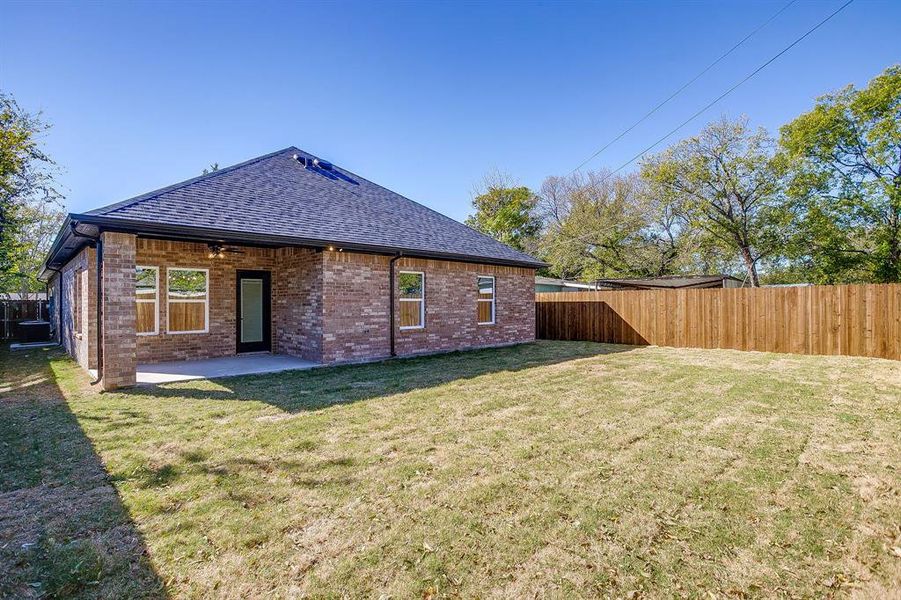 Back of property with a fenced backyard, brick siding, a shingled roof, a patio, and a ceiling fan