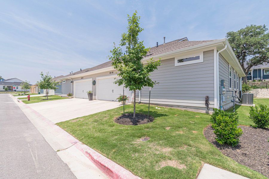 View of front of property featuring driveway, a garage, a front lawn, and cooling unit