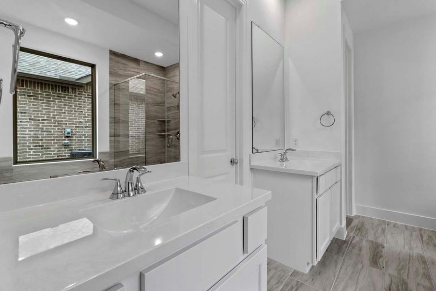 Bathroom featuring a stall shower and two vanities Bathroom featuring a stall shower and two vanities