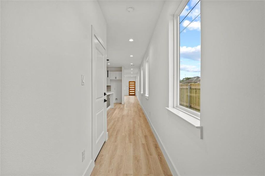 Hall with light wood finished floors, recessed lighting, and baseboards Hall with light wood finished floors, recessed lighting, and baseboards
