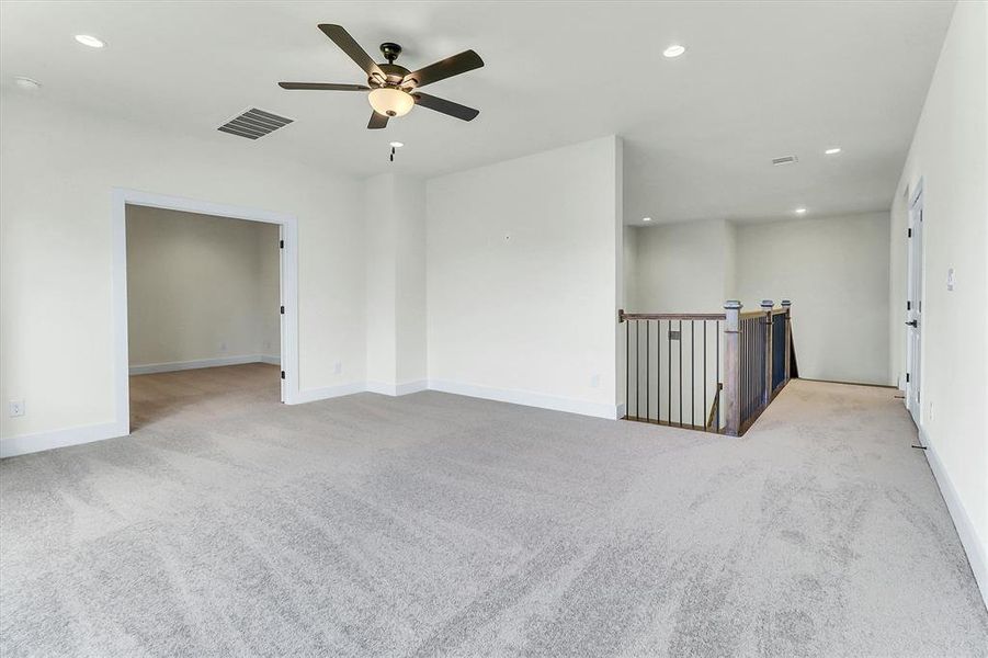 Expansive carpeted room featuring a ceiling fan with integrated lighting, recessed lighting, and a doorway to an additional room Expansive carpeted room featuring a ceiling fan with integrated lighting, recessed lighting, and a doorway to an additional room