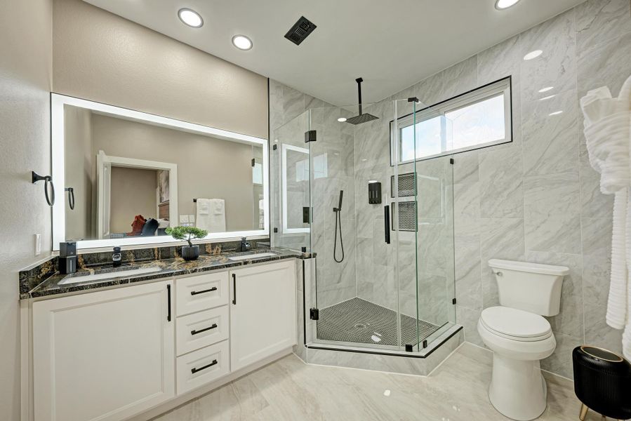 A glass-enclosed walk-in shower and stone-topped vanity define this modern bathroom. A glass-enclosed walk-in shower and stone-topped vanity define this modern bathroom.