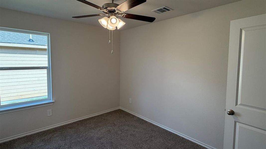Room featuring neutral wall tones, carpet flooring, a window with horizontal blinds, a ceiling fan with integrated lighting, and a paneled door with a brushed nickel knob