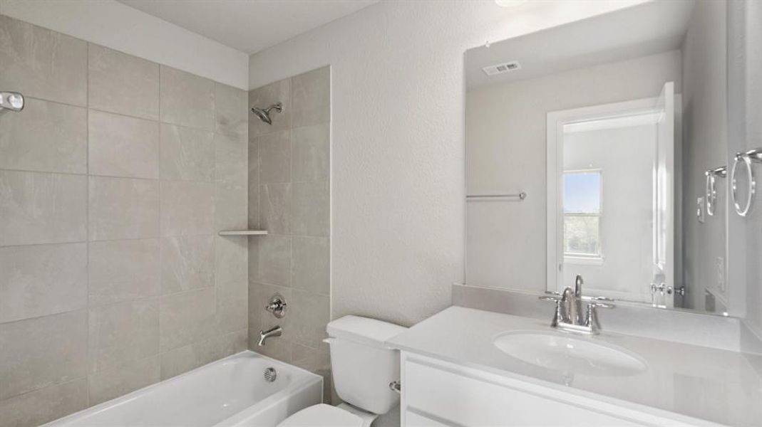 Bathroom with shower / bath combination, vanity, and a textured wall Bathroom with shower / bath combination, vanity, and a textured wall