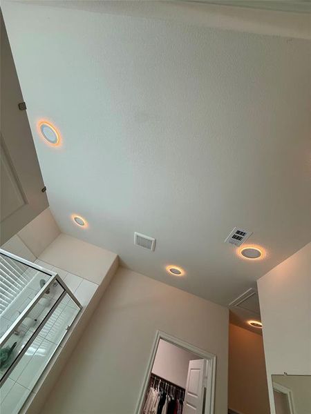 Recessed ceiling lighting illuminating a room with a frameless glass shower enclosure