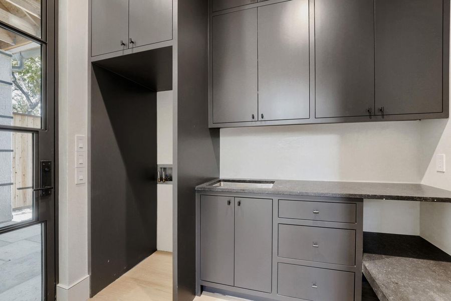 A well-appointed laundry area offers extensive cabinet storage and a utility sink for convenience.