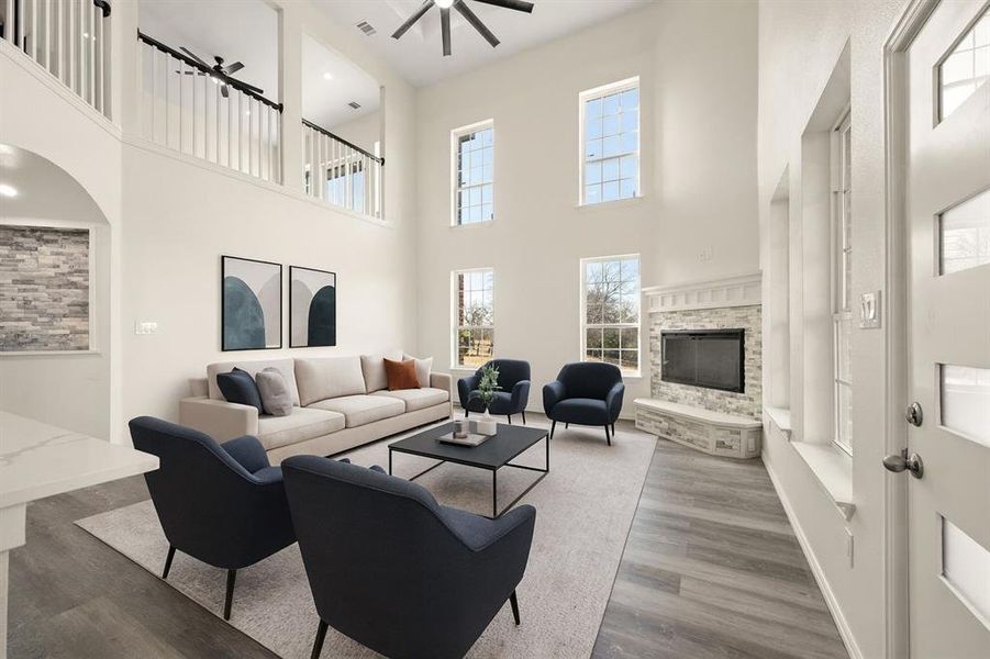 Living room featuring a fireplace, wood finished floors, ceiling fan, a towering ceiling, and recessed lighting Living room featuring a fireplace, wood finished floors, ceiling fan, a towering ceiling, and recessed lighting
