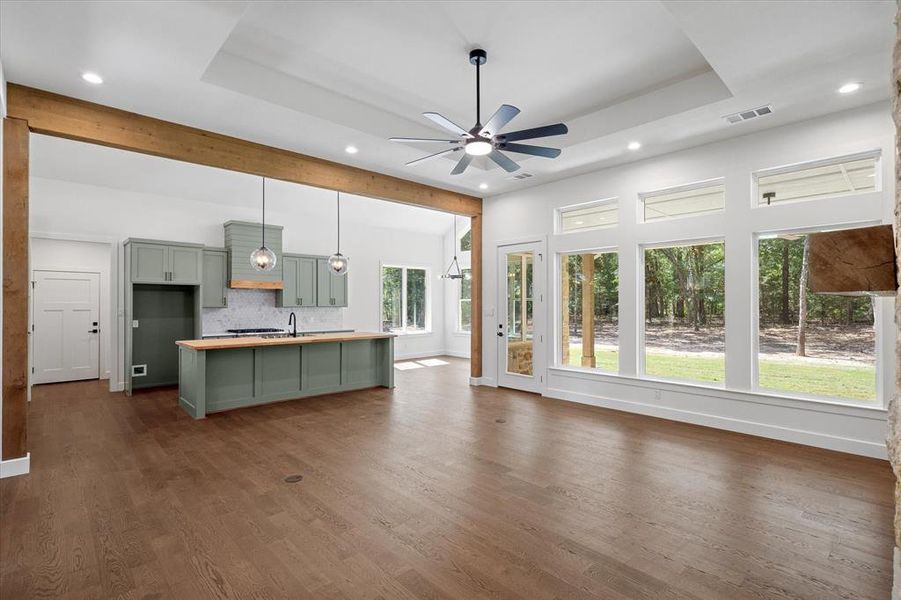 Open concept with ample windows for natural lighting, raised ceiling, a custom fireplace mantle and quality luxury vinyl plank floors Open concept with ample windows for natural lighting, raised ceiling, a custom fireplace mantle and quality luxury vinyl plank floors