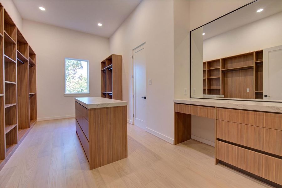 Primary closet with vanity space and island with drawers. Primary closet with vanity space and island with drawers.