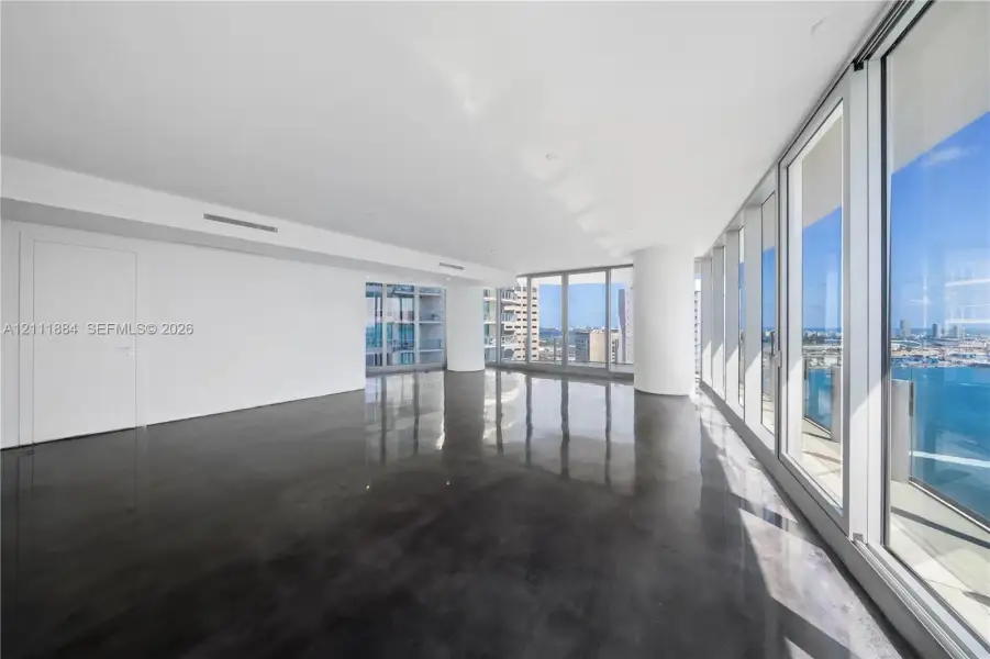 Expansive interior space featuring high-gloss polished concrete flooring, floor-to-ceiling glass panel walls, and cylindrical architectural columns Expansive interior space featuring high-gloss polished concrete flooring, floor-to-ceiling glass panel walls, and cylindrical architectural columns