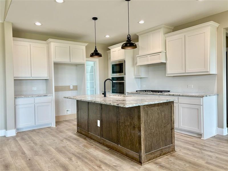 Kitchen with appliances with stainless steel finishes, white cabinetry, light wood-type flooring, an island with sink, and recessed lighting Kitchen with appliances with stainless steel finishes, white cabinetry, light wood-type flooring, an island with sink, and recessed lighting