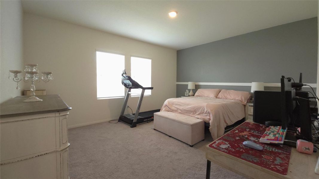 Spacious room featuring neutral carpet flooring, a vaulted ceiling, and two large windows
