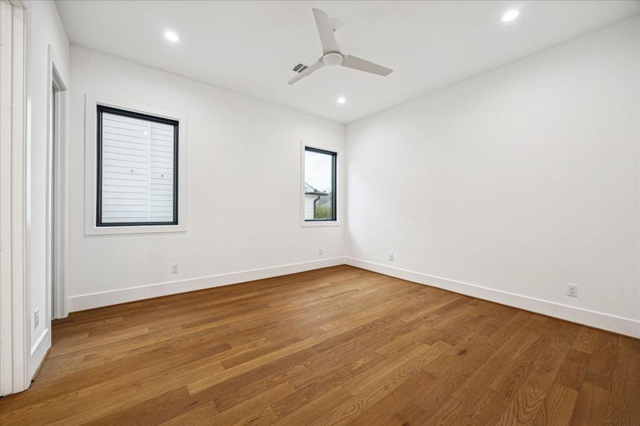 Crisp architectural lines define this secondary bedroom, highlighted by wide plank hardwoods, tall 8 foot doors, and clean framed windows that balance natural light with privacy. The generous footprint supports multiple furniture configurations, while the en suite layout keeps the space feeling elevated and thoughtfully designed. Crisp architectural lines define this secondary bedroom, highlighted by wide plank hardwoods, tall 8 foot doors, and clean framed windows that balance natural light with privacy. The generous footprint supports multiple furniture configurations, while the en suite layout keeps the space feeling elevated and thoughtfully designed.
