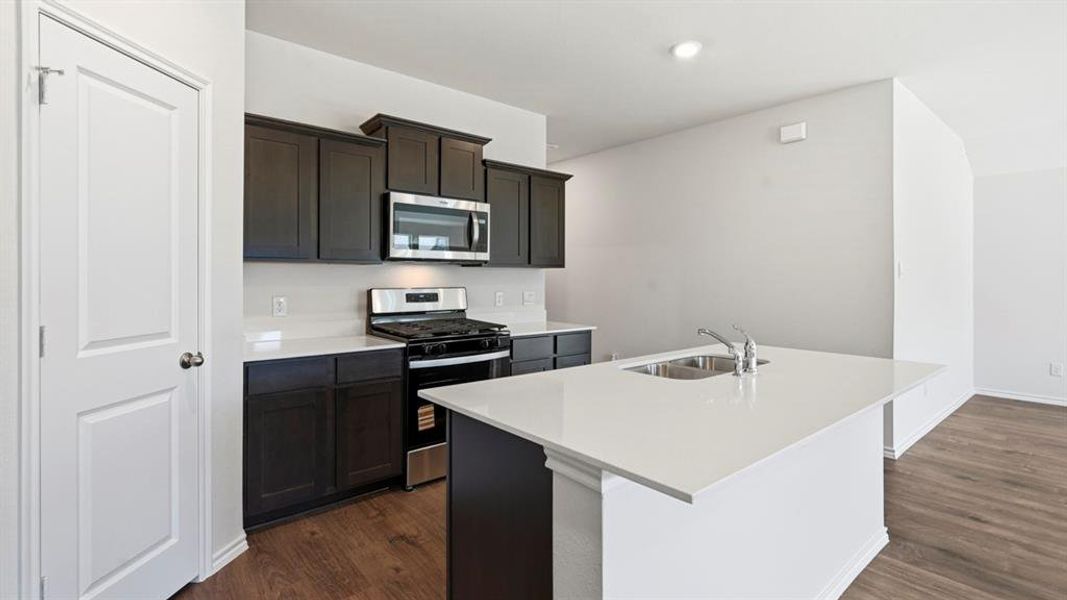 Kitchen with stainless steel appliances, an island with sink, dark wood-style floors, light stone countertops, and recessed lighting Kitchen with stainless steel appliances, an island with sink, dark wood-style floors, light stone countertops, and recessed lighting