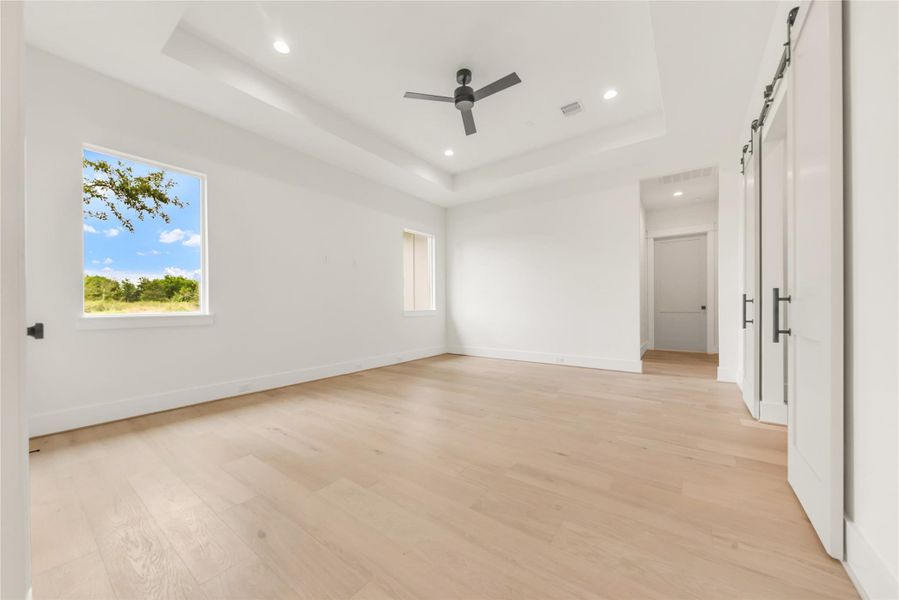 Spare room featuring a barn door, recessed lighting, light wood-style flooring, and a ceiling fan