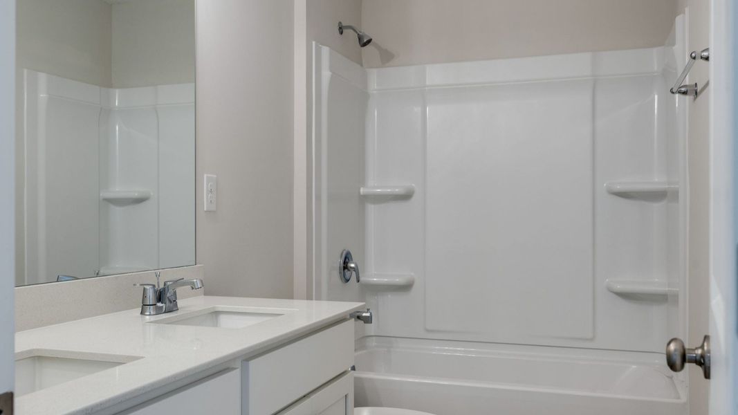 Secondary bathroom with elevated touches of dual sinks and bathtub