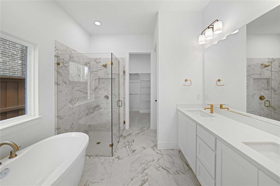 Full bath with a marble finish shower, a freestanding tub, double vanity, a walk in closet, and light marble finish flooring Full bath with a marble finish shower, a freestanding tub, double vanity, a walk in closet, and light marble finish flooring