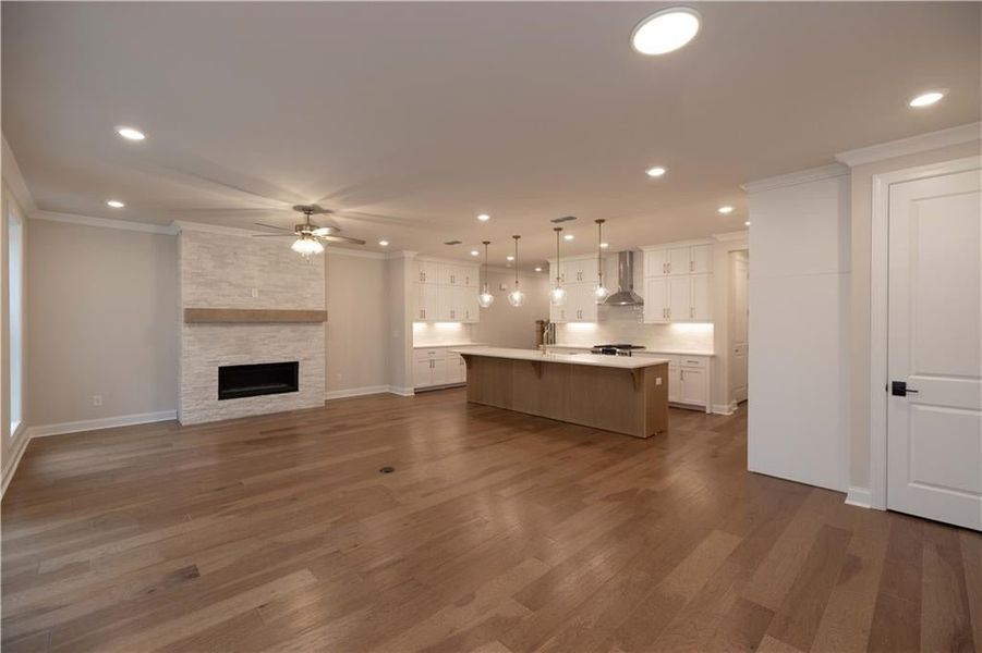 Kitchen with open floor plan, pendant lighting, a breakfast bar area, white cabinetry, and dark wood-style flooring
