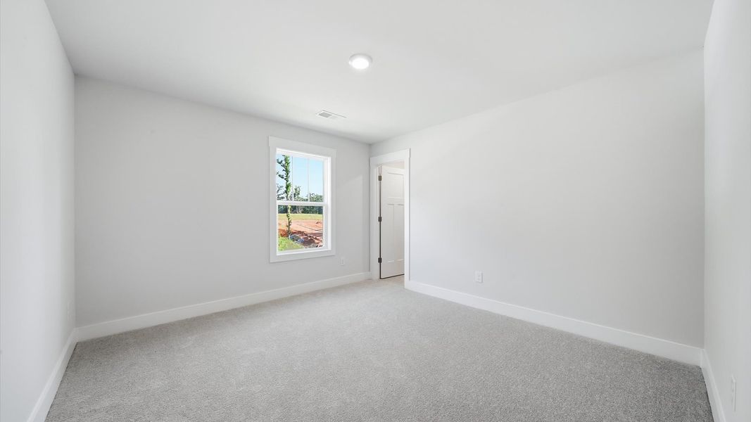 Inviting bedroom with tasteful finishes and large windows that create a fresh, open ambiance by DRB Homes