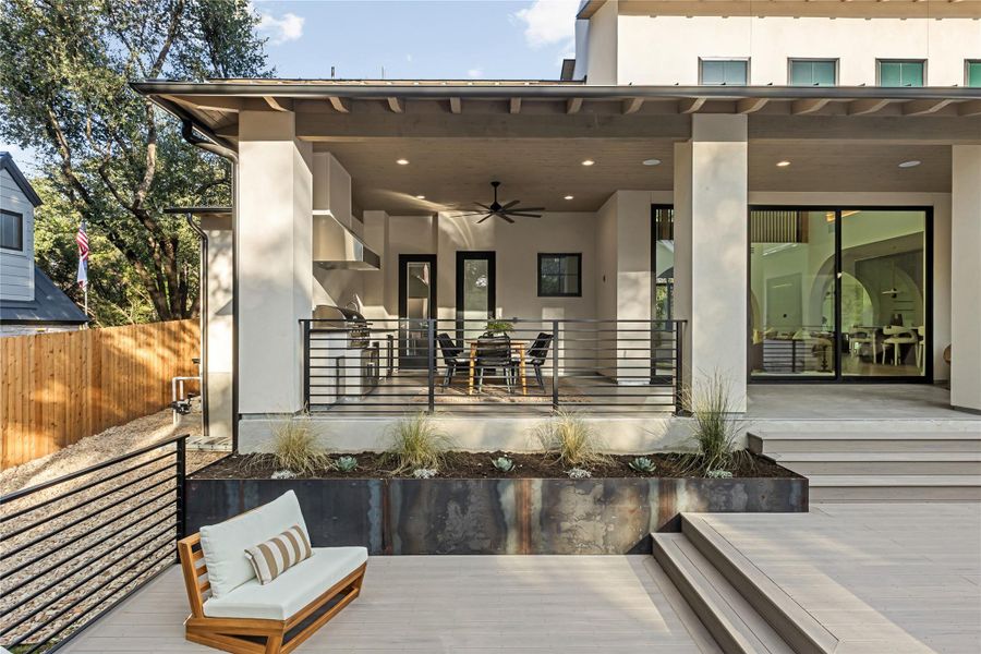 An inviting outdoor dining area features a complete kitchen setup with a grill and a ceiling fan for comfortable entertaining.