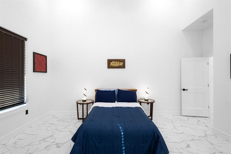 Bedroom featuring baseboards and light marble finish floors
