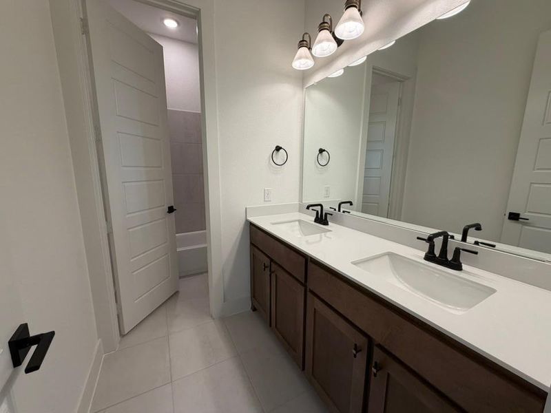 Full bathroom with double vanity, light tile patterned flooring, and shower / bath combination
