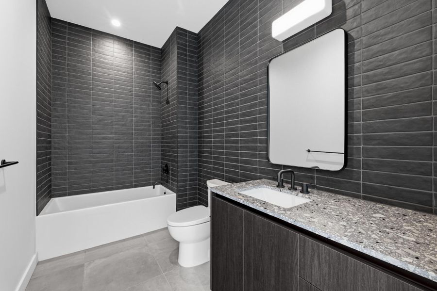The secondary bathroom features floor to ceiling tile with a tub/shower combination