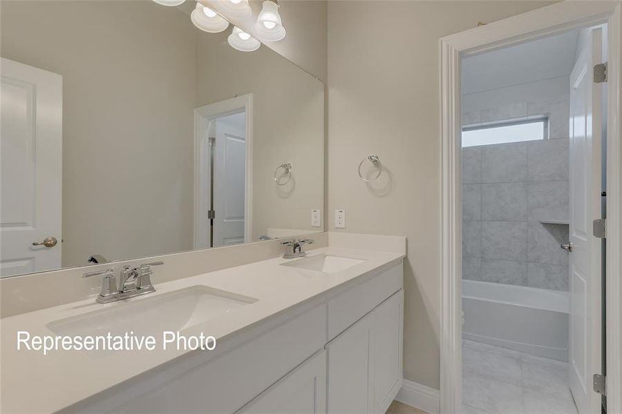 Bathroom featuring tiled shower / bath combo, tile patterned floors, and double sink vanity