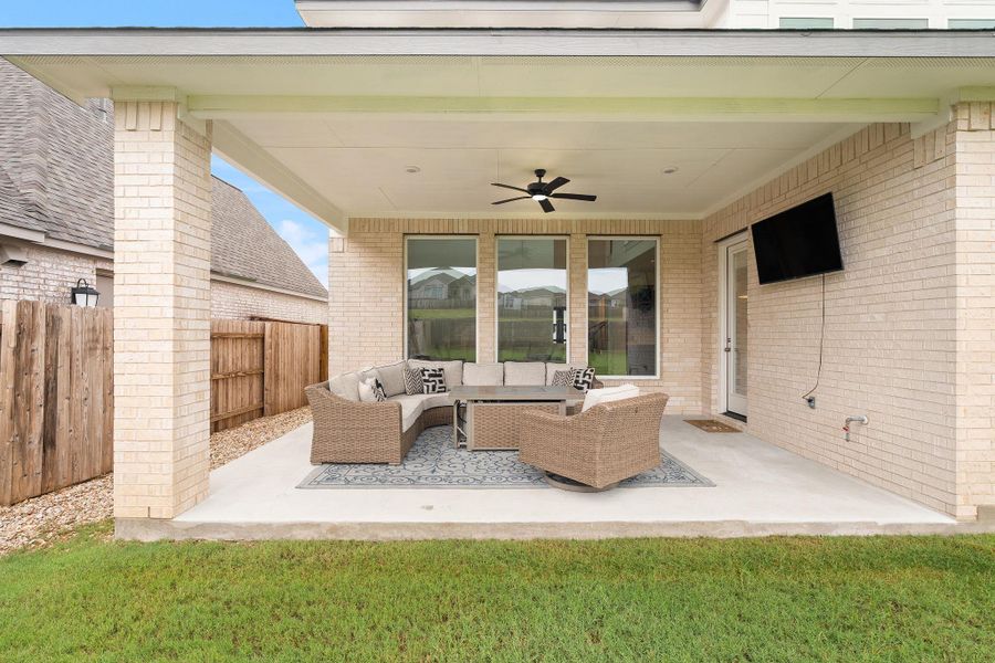 An inviting covered patio, perfect for enjoying outdoor moments, features a ceiling fan and ample space for entertaining.