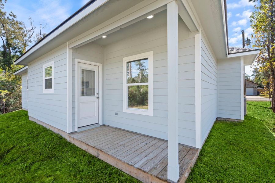 The covered back porch provides a sheltered entryway and a cozy outdoor spot to relax. The wooden deck offers overhead recessed lighting for added comfort and visibility.