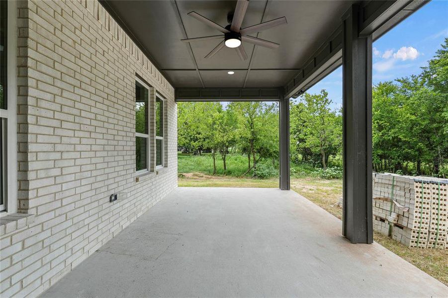 View of patio / terrace with ceiling fan and view of wooded area