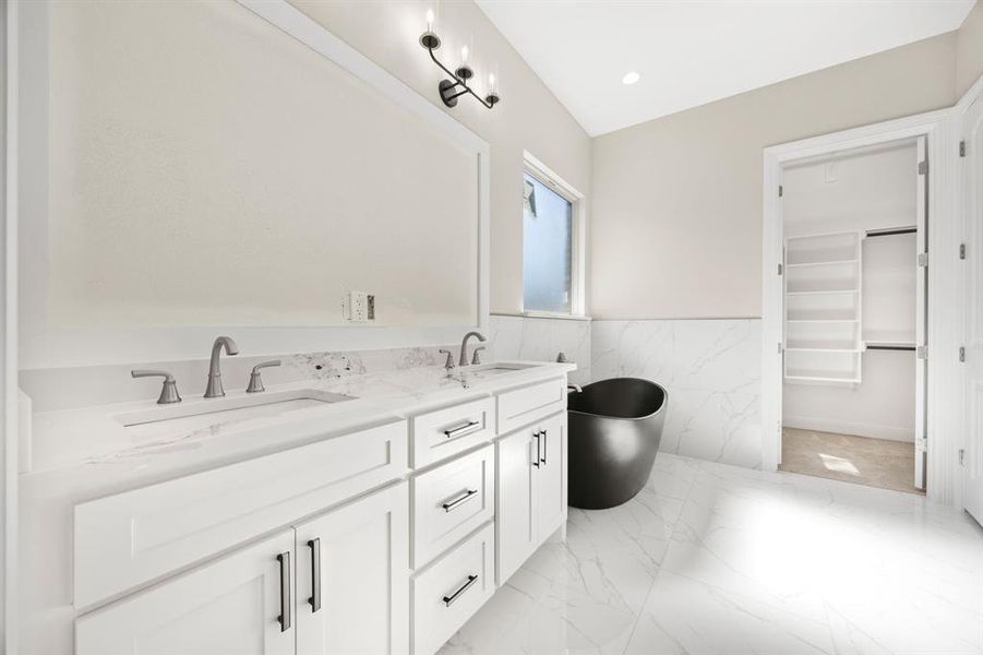 Bathroom with tile patterned flooring, tile walls, a tub to relax in, and vanity