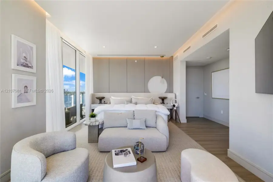 Floor-to-ceiling windows, custom paneled headboard wall with integrated lighting, wood-finish flooring, and recessed ceiling lighting Floor-to-ceiling windows, custom paneled headboard wall with integrated lighting, wood-finish flooring, and recessed ceiling lighting