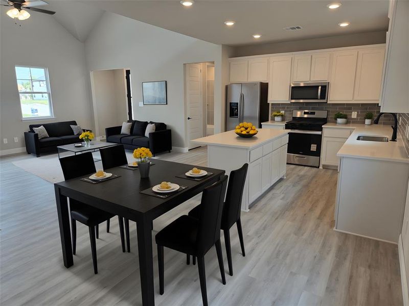 Kitchen with appliances with stainless steel finishes, open floor plan, white cabinetry, decorative backsplash, and light wood-style flooring