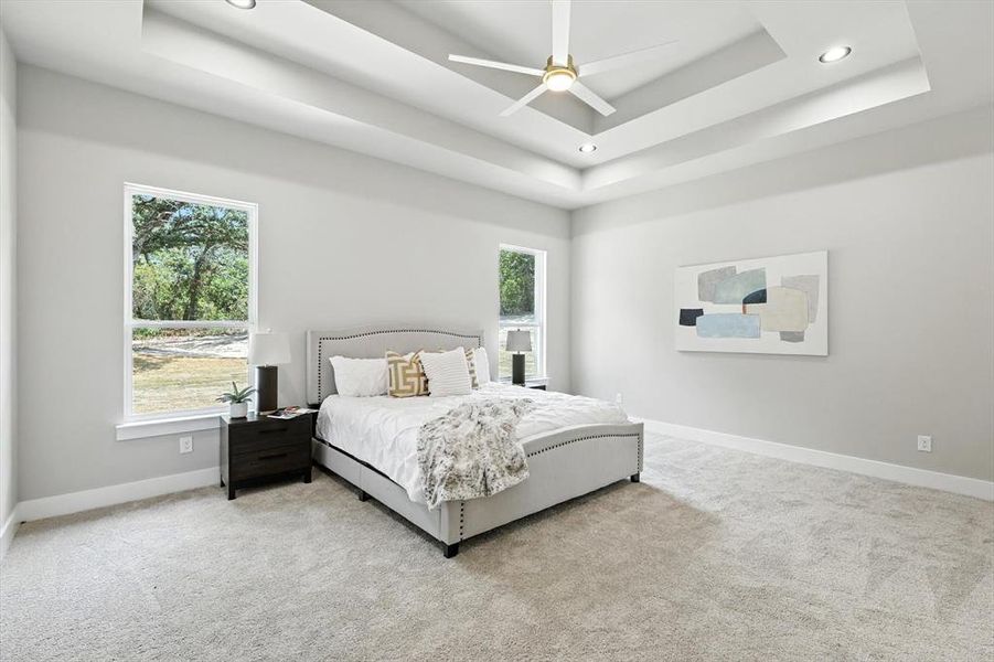 Carpeted bedroom featuring a tray ceiling, ceiling fan, and recessed lighting