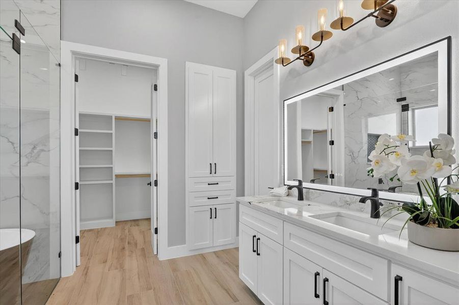 Dual vanity with white cabinetry, matte black fixtures, and a large illuminated mirror