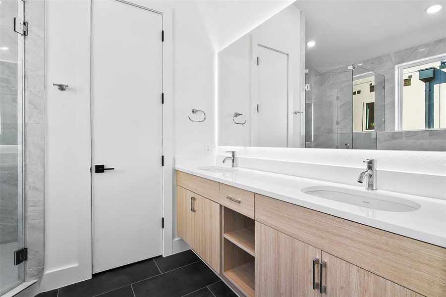 Bathroom featuring tile patterned flooring, vanity, and an enclosed shower