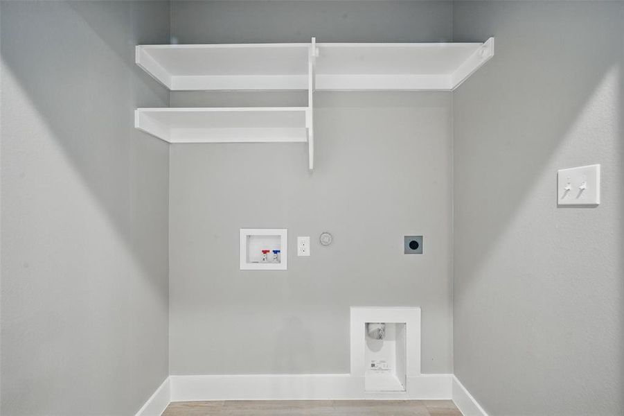 Laundry area with hookup for an electric dryer, gas dryer hookup, hookup for a washing machine, baseboards, and wood finished floors