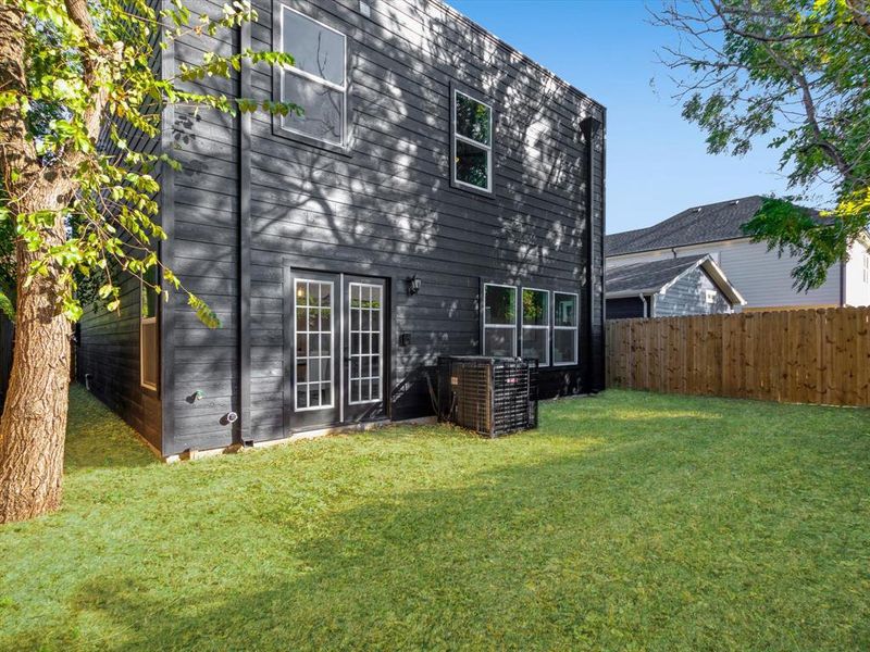 Back of property featuring a lawn and cooling unit