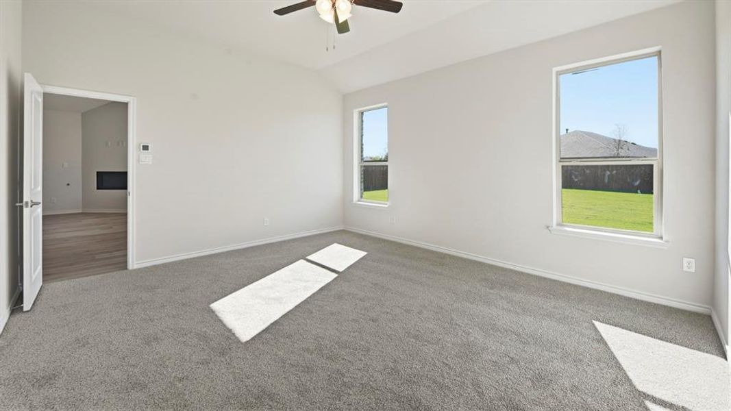 Empty room with vaulted ceiling, carpet, and a ceiling fan