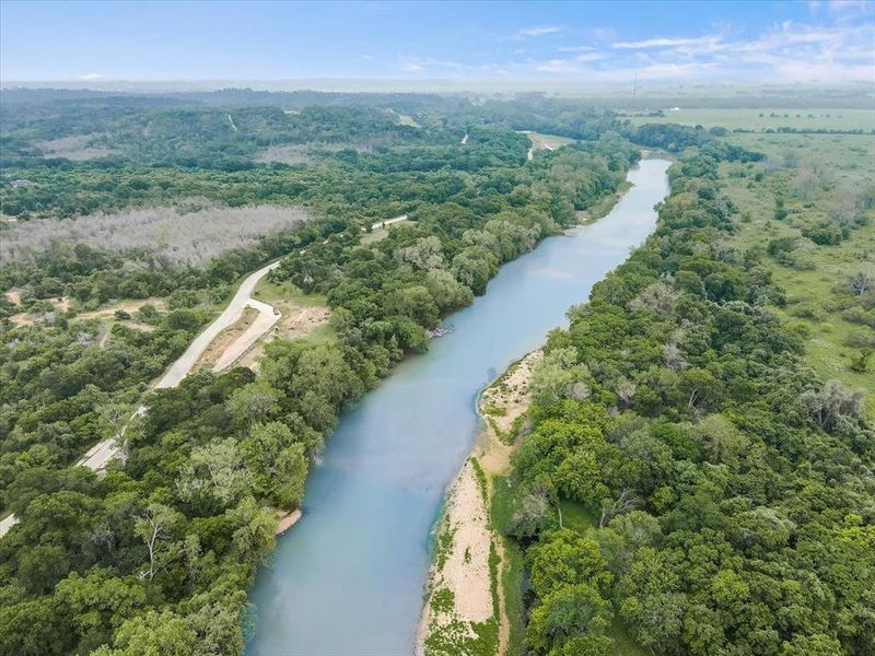This aerial view showcases a river and surrounding wooded areas, offering a serene natural setting